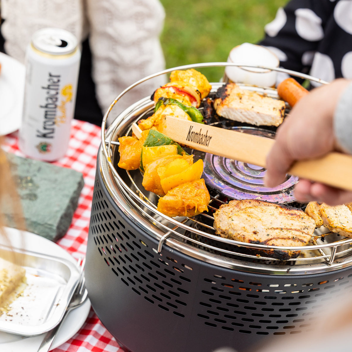 Freunde im Garten beim Grillen mit dem rauchfreien Grill von Krombacher.