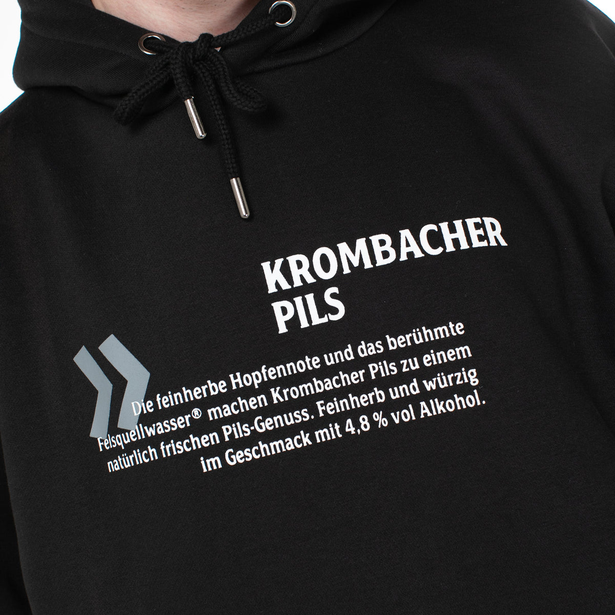 Schwarzer Hoodie mit weißem Text 'Krombacher Pils' und Beschreibung des Biers mit 4,8 % Alkohol.