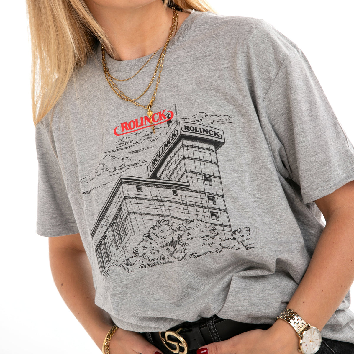Grau meliertes T-Shirt mit schwarzer Linienzeichnung von Rolinck Brauerei und rotem Schriftzug 'ROLINCK' auf der Brust, getragen von einer Person mit goldener Kette und Armbanduhr