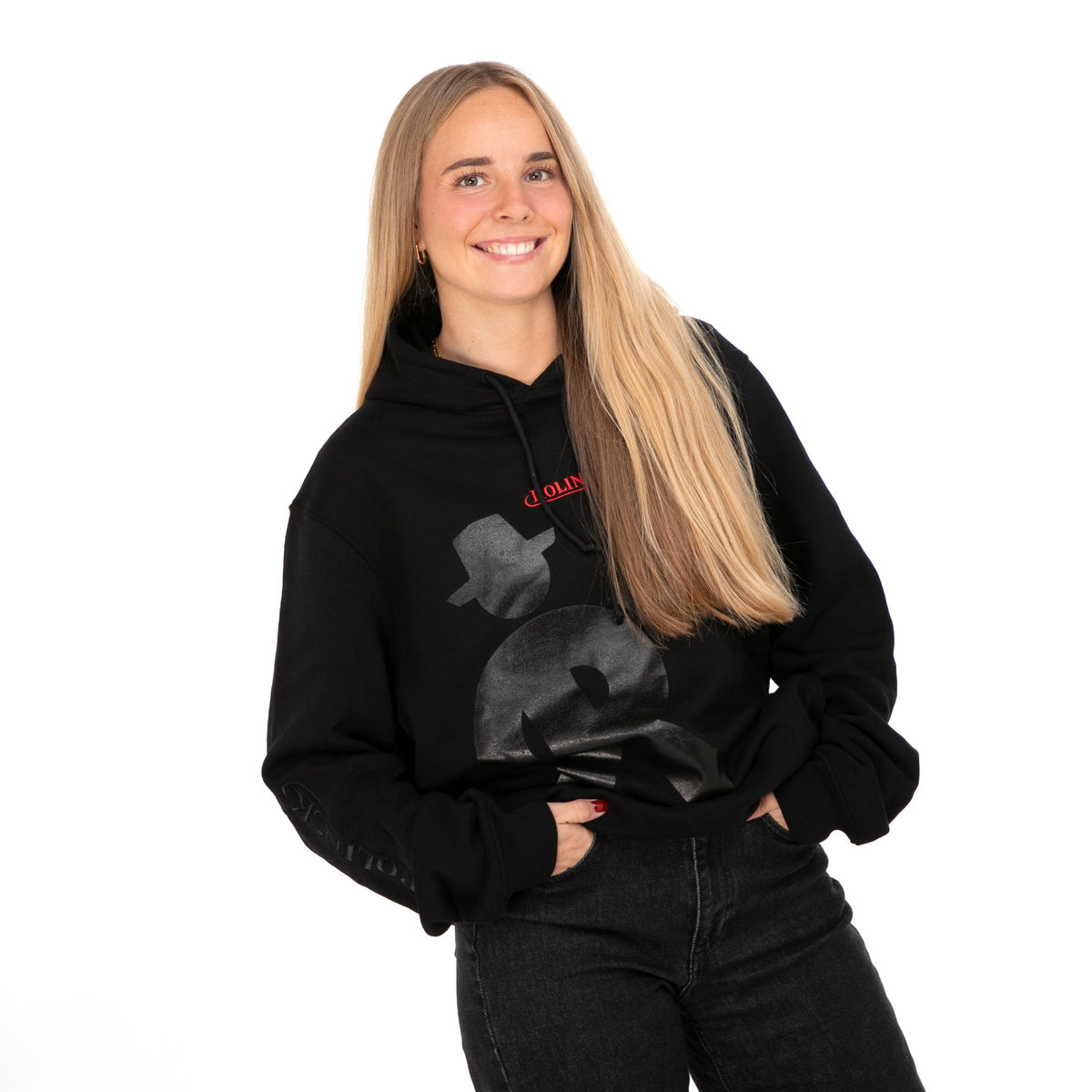 Person mit langem, glattem, blondem Haar trägt schwarzen Hoodie mit Rolinck Männchen und rotem "ROLINCK' Schriftzug auf der Brust, schwarze Hose.