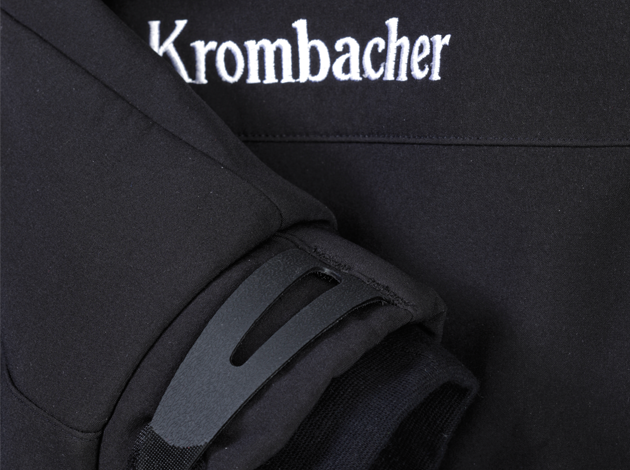 Nahaufnahme eines schwarzen Softshelljackenärmels mit Klettverschluss und weißem Schriftzug 'Krombacher' auf dem Stoff