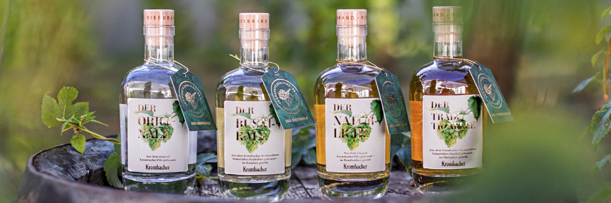 Vier Flaschen Kornbacher Bierbrände mit verschiedenen Etiketten im Freien