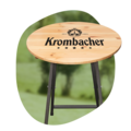 Stehtisch mit rundem Holzplatte und schwarzem Metallgestell, Platte mit Schriftzug 'Krombacher' und Logo.