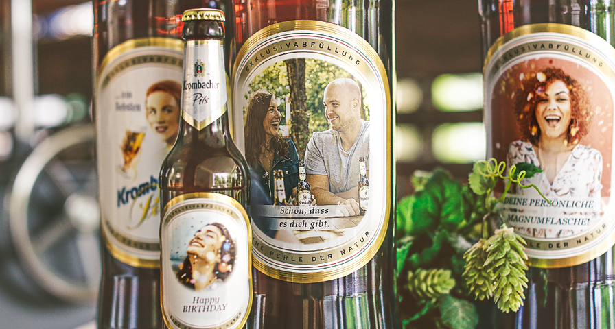Mehrere Krombacher Bierflaschen mit individuellen Etiketten, darunter ein Geburtstagsmotiv und persönliche Grußtexte