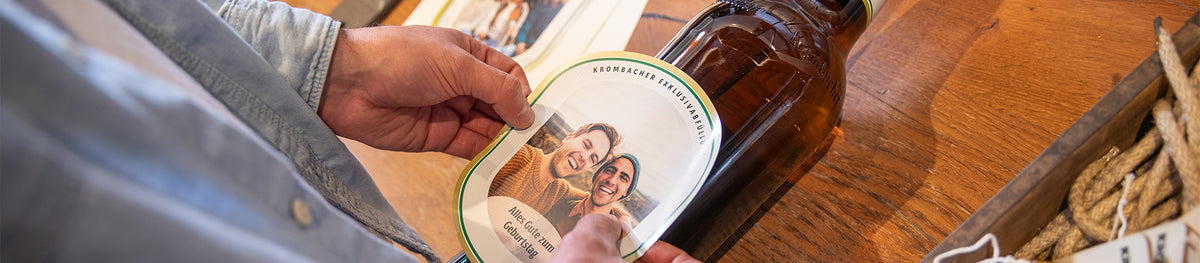 Krombacher Manufaktur: personalisiertes Etikett wird auf eine große Bierflasche geklebt.