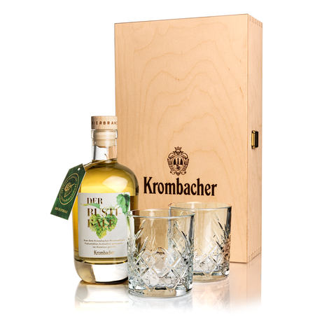 Flasche Krombacher Bierbrand mit zwei Kristallgläsern vor einer Holzgeschenkbox mit Krombacher-Logo