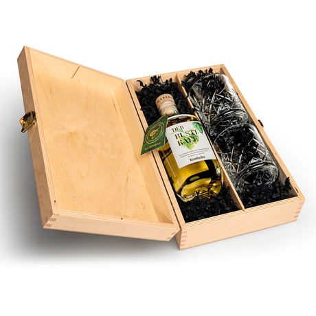 Offene Holzkiste mit einer Flasche Krombacher Bierbrand und zwei Kristallgläsern in schwarzem Füllmaterial