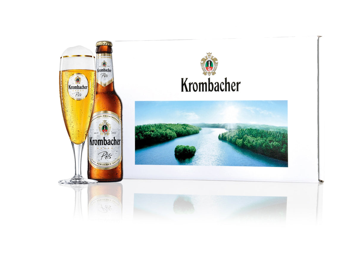 Krombacher Pils Bierflasche und Glas, neben einer Krombacher Geschenkbox mit Krombacher See Aufdruck.