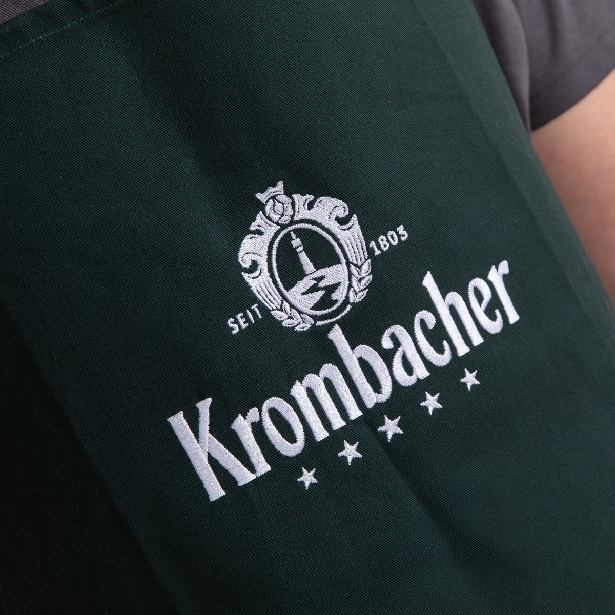 Grüne Grillschürze mit weißem Krombacher-Logo und Schriftzug