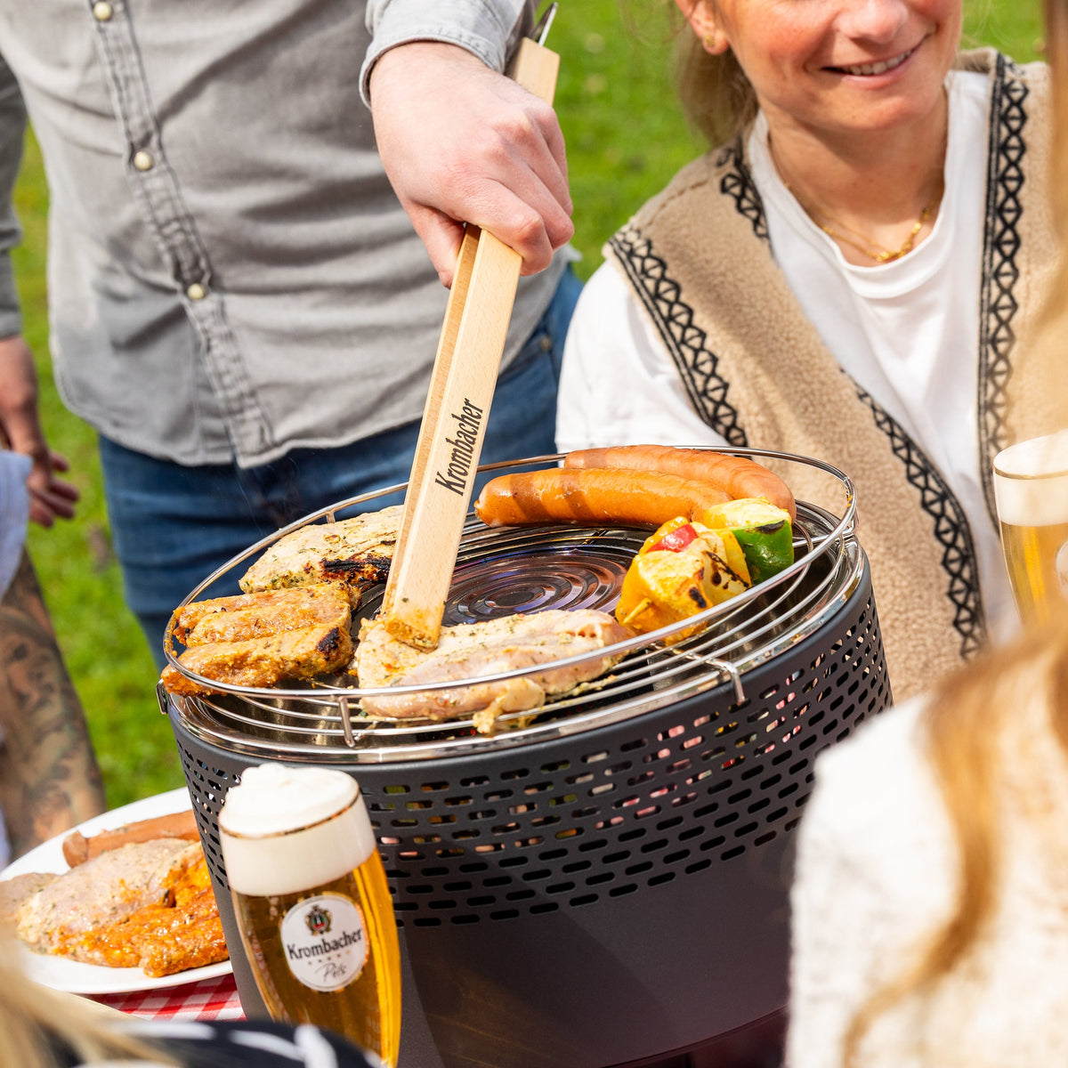 Freunde im Garten beim Grillen mit dem rauchfreien Grill von Krombacher.