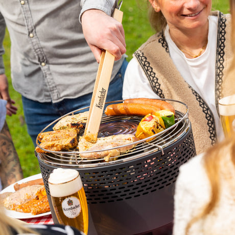 Freunde im Garten beim Grillen mit dem rauchfreien Grill von Krombacher.