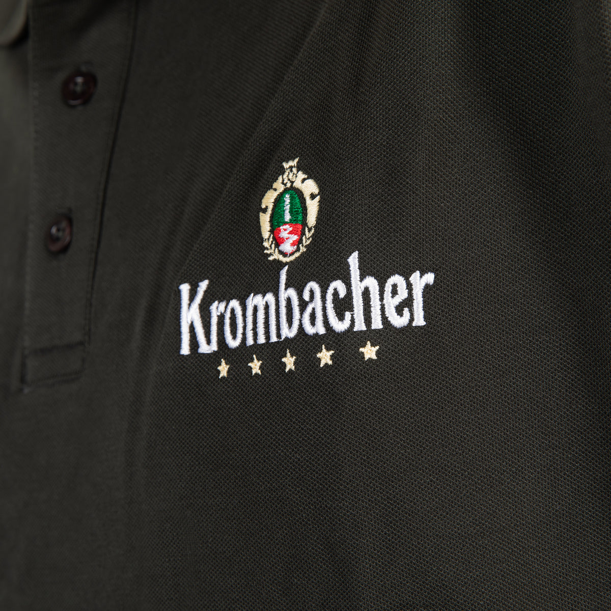 Dunkelgrünes Poloshirt mit gesticktem Krombacher-Logo und fünf Sternen unter dem Schriftzug