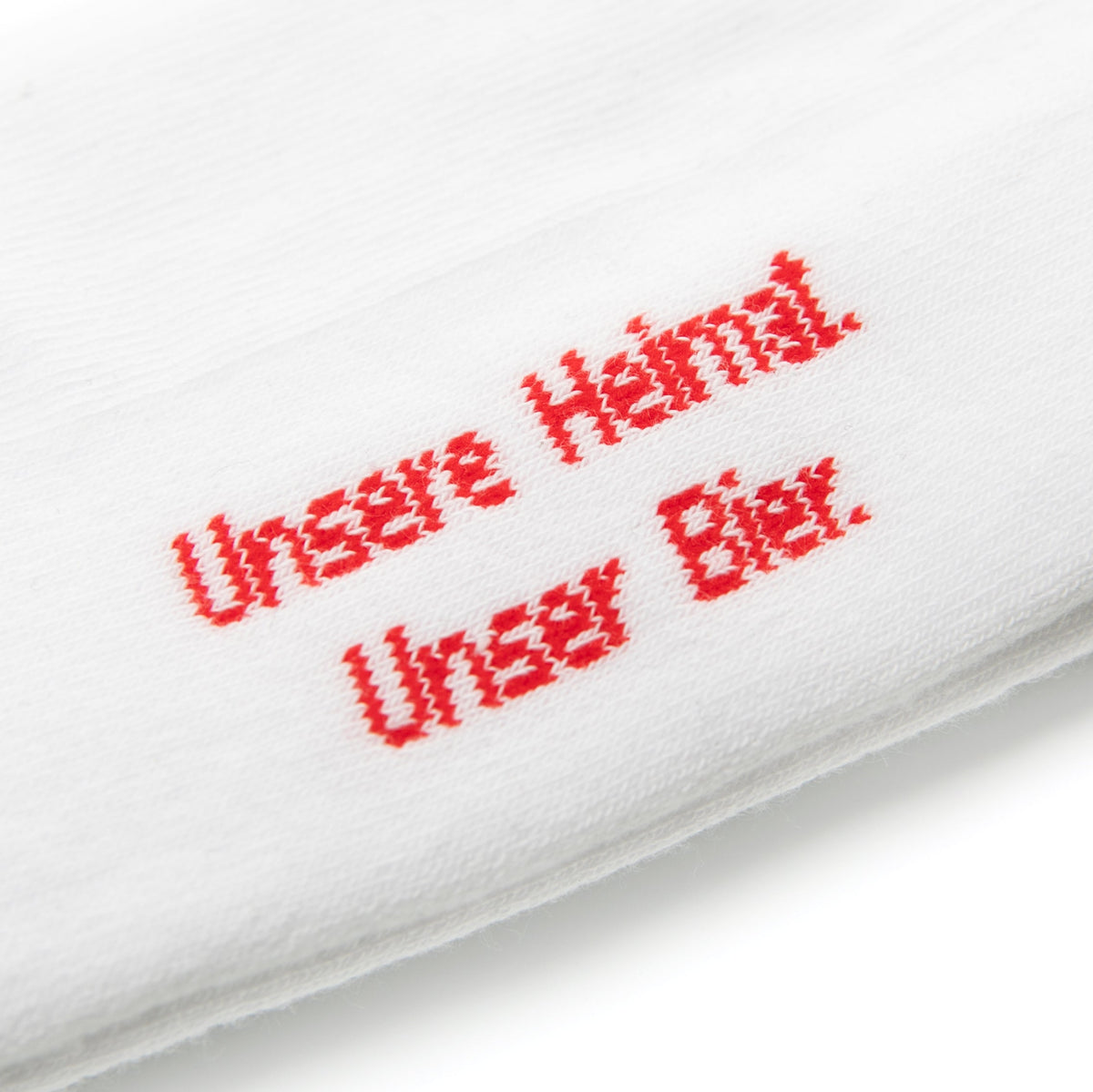Nahaufnahme von Socke mit roter Stickerei 'Unsere Heimat Unser Bier' in diagonaler Schrift.