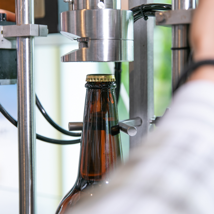 Krombacher Manufaktur: Pils-Flasche wird mit Kronkorken verschlossen.