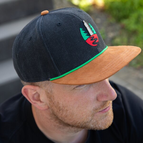 Krombacher Snapback mit braunem Schild und grünem Akzent.