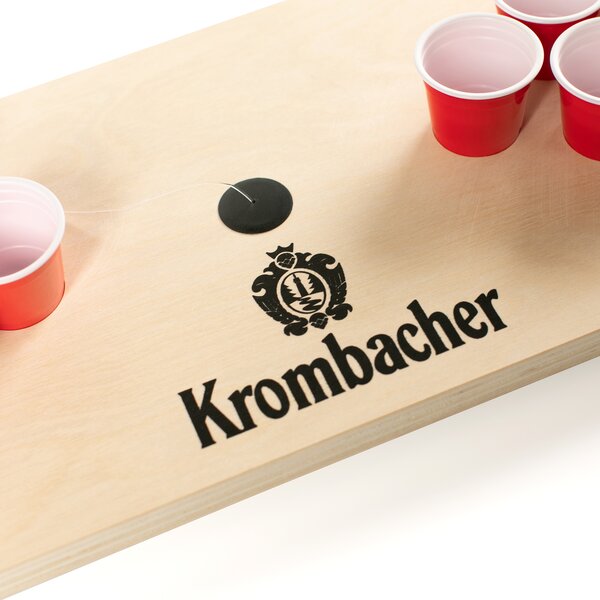 Nachaufnahme Krombacher Mini Beerpong Spiel mit roten Bechern auf Holzplatte.
