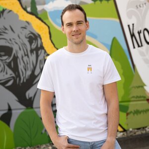 Ein Mann in einem weißen T-Shirt mit zwei anstoßenden Krombacher Gläsern auf der Brust, vor einer bunten Wand. Ein Mann in einem weißen T-Shirt mit zwei anstoßenden Krombacher Gläsern auf der Brust, vor einer bunten Wand.