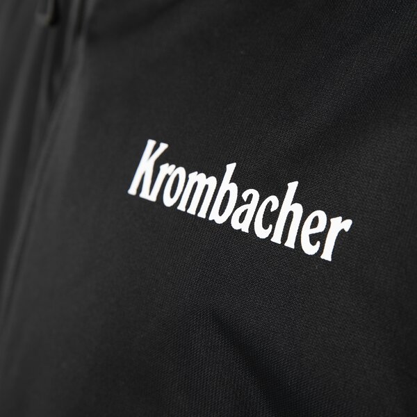 Schwarze Regenjacke mit weißem Schriftzug 'Krombacher' auf der Brust.