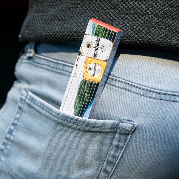 Krombacher Zollstock mit Bierflaschenmotiv in der Gesäßtasche einer hellblauen Jeans.