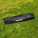 Schwarze Tragetasche mit dem Schriftzug 'Krombacher' liegt auf grünem Gras.