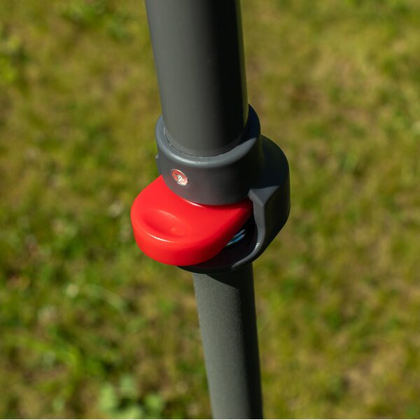 Nahaufnahme eines grauen Metallrohrs mit rotem Verriegelungshebel im Freien auf grünem Gras.