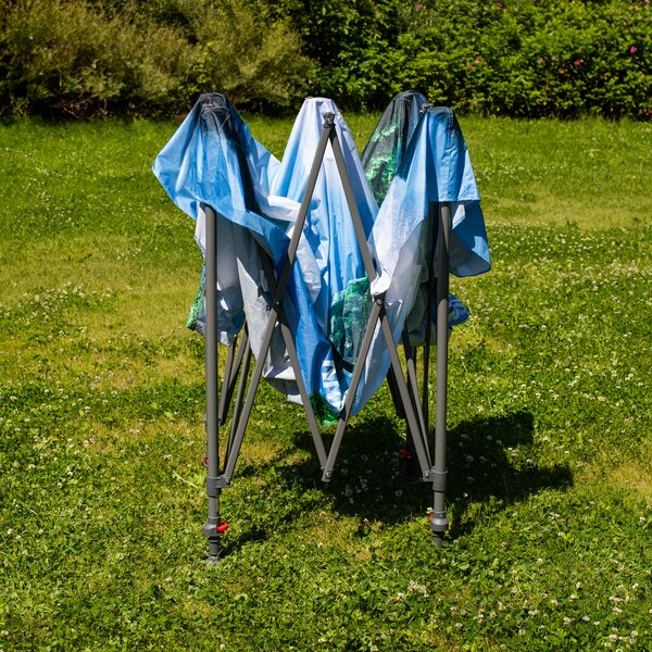 Zusammengeklappter Pavillon mit blau-weißem Stoff auf grünem Gras im Garten.