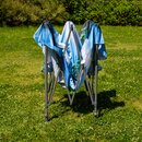 Zusammengeklappter Pavillon mit blau-weißem Stoff auf grünem Gras im Garten.