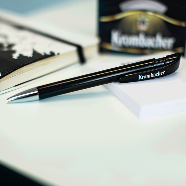 Krombacher Kugelschreiber liegt auf weißem Notizblock.