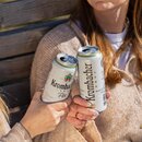 Zwei Frauen stoßen mit Krombacher Pils in der Dose an und sitzen auf einer Holzbank.