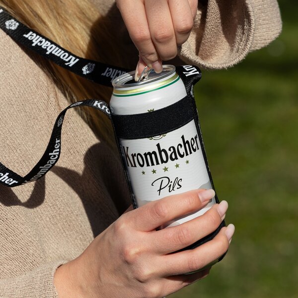7607_krombachershop_Getraenkehalter_Mood_002 Hand zieht Lasche an einer Krombacher Pils Dose in schwarzem Getränkehalter mit Krombacher-Schriftzug.