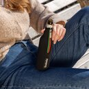 Person sitzt auf einer Holzbank, hält eine Krombacher Flasche in einem schwarzen Neopren-Flaschenkühler mit Reißverschluss und Logo.