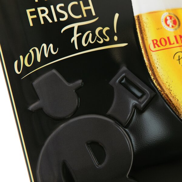 Schwarzes Blechschild mit erhabenen Buchstaben und Teil eines Bierglases, Text 'FRISCH vom Fass!' in goldener Schrift.