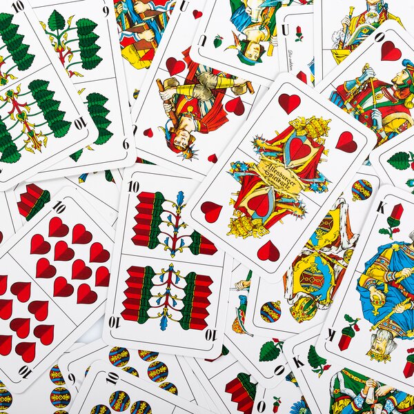 Mehrere durcheinanderliegende Spielkarten des deutschen Blattmusters mit Herz, Eichel, Schellen und Gras als Farben.