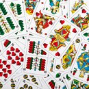 Mehrere durcheinanderliegende Spielkarten des deutschen Blattmusters mit Herz, Eichel, Schellen und Gras als Farben.