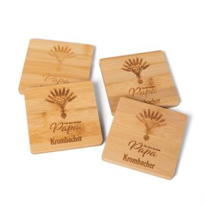 Vier Untersetzer aus Holz mit Gravur eines Weizenbündels und der Schrift 'Für den besten Papa Krombacher'.