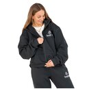 Frau steht mit Händen in den Taschen einer dunkelgrünen Jogginghose mit Krombacher-Logo, trägt weiße Crop-T-Shirt, dunkelgrünen Jacke