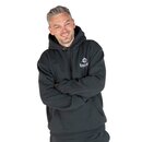 Mann mit verschränkten Armen trägt dunkelgrünen Kapuzenpullover mit weißem Krombacher-Logo auf der Brust