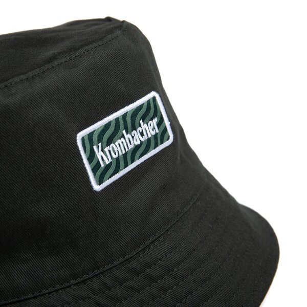 Seitenansicht von dunkelgrünem Bucket Hat mit rechteckigem Krombacher-Logo auf der Vorderseite