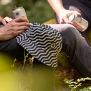 Gestreifter Bucket-Hut mit Krombacher Wappen liegt auf dem Knie einer Person, die eine Getränkedose hält, im Freien sitzend