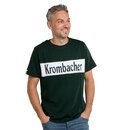 Mann mit grauem Haar trägt dunkelgrünes T-Shirt mit weißem Rechteck und Schriftzug 'Krombacher' und hat die Hände in den Hosentaschen