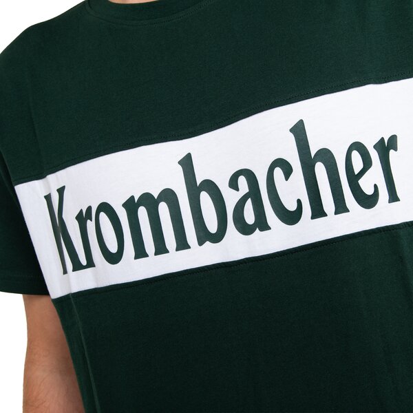 Oberkörper eines Mannes mit dunkelgrünem T-Shirt, das einen weißen Querstreifen mit dem Schriftzug 'Krombacher' trägt