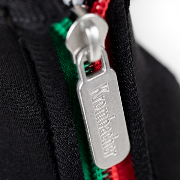 Metallischer Reißverschlussanhänger mit dem Schriftzug 'Krombacher' an einem Neopren-Flaschenkühler.