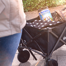 Schwarzer Bollerwagen mit Krombacher Frischefass und Tasche, Teil einer Person in Jeans und Jacke im Vordergrund.