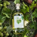 Flasche Krombacher Bierbrand 'Der Rustikale' umgeben von Hopfenpflanzen auf Holzuntergrund.