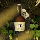 Braune 1-Liter-Flasche Krombacher Pils mit Bügelverschluss und Etikett, umgeben von Hopfenpflanzen.